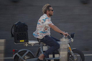Arto Saari riding an electric bike with his camera gear in tow.