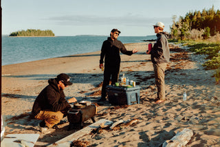 Three people hanging out and cooking on a beach in Nova Scotia.