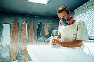 A surfboard shaper working on a foam blank.